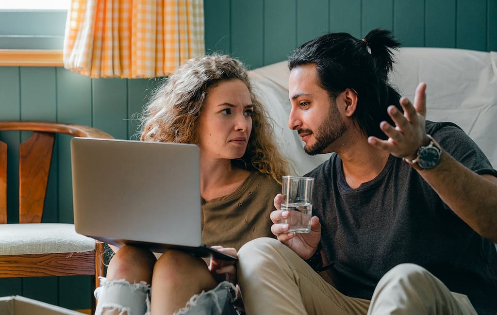 Couple talking while looking at a laptop