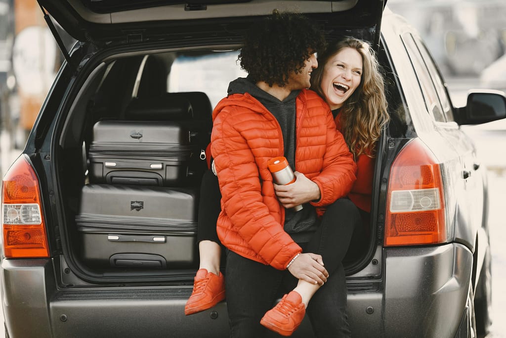 Couple laughing as they pack their luggage in the car to go on to their vacation.