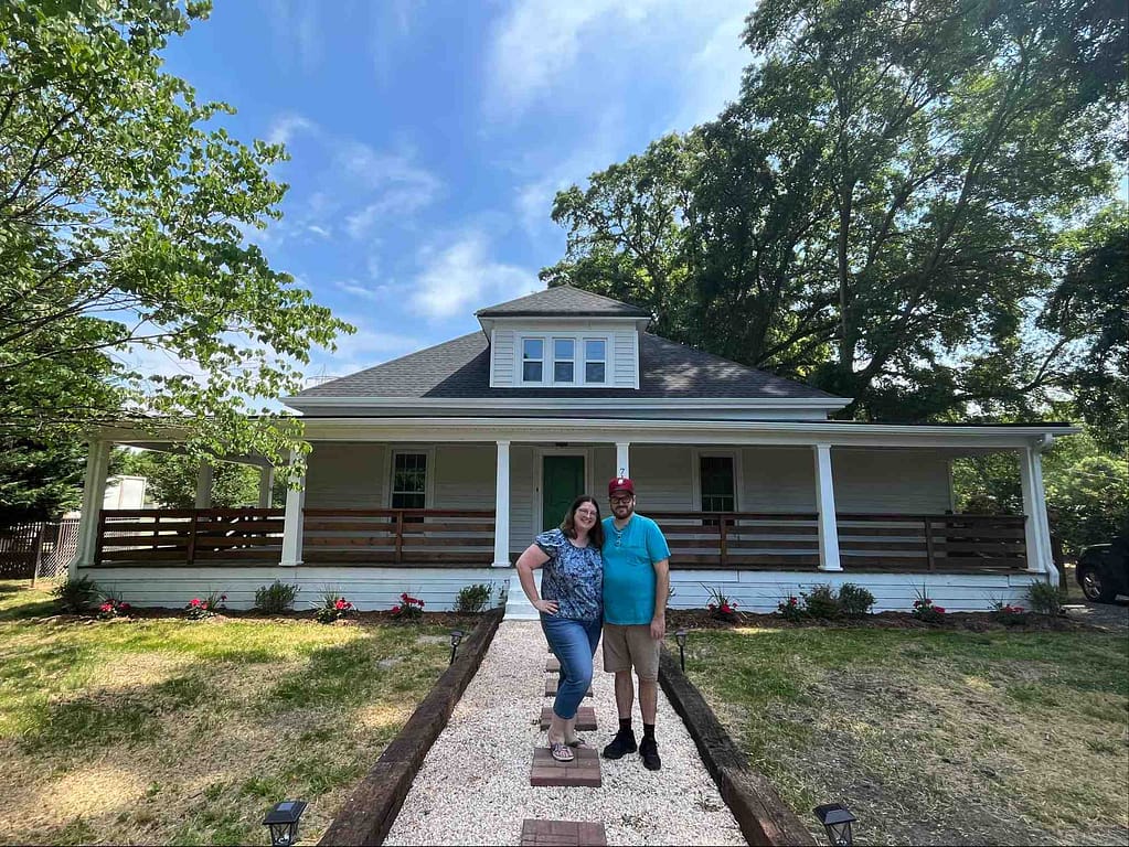 Ben and Erica in front of their white house with porch