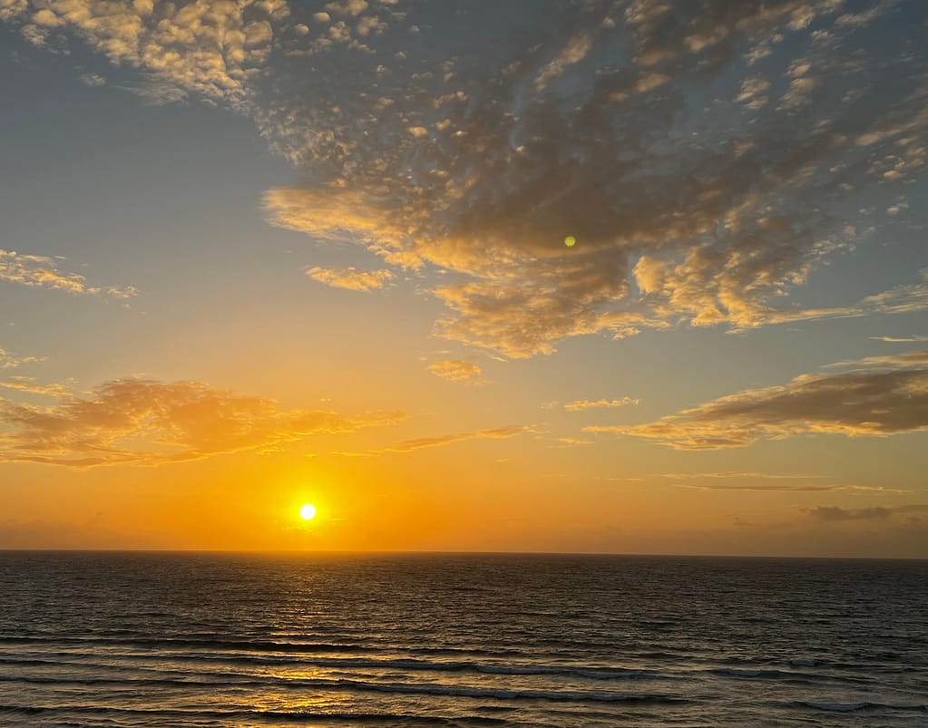View of the sun low in the sky above the ocean from a cruise ship
